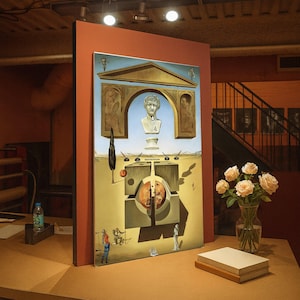May include: A framed surrealist painting featuring a bust, architectural elements, and a landscape with figures. The artwork is displayed on a wooden table, with a vase of roses and a stack of books nearby. The painting has a complex composition and a dreamlike quality.