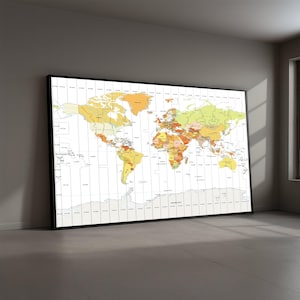 May include: A large framed world map with a black border, leaning against a gray wall. The map features a colorful depiction of the continents and countries, with a focus on geographical details and time zones. The color palette includes shades of yellow, orange, green, and brown.