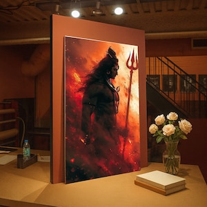 May include: A framed artwork depicting a deity figure with long hair, holding a trident, set against a fiery red background. The artwork is displayed on a table with a vase of white roses and a stack of books.
