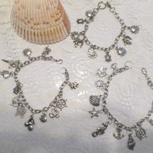 May include: Three silver charm bracelets with various nautical themed charms, including a starfish, seashell, anchor, and ship's wheel.