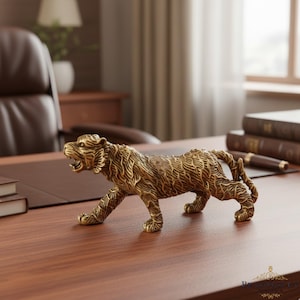 May include: A detailed brass tiger figurine with an open mouth, positioned on a wooden desk. The sculpture has intricate etched details and is set against a blurred office background with books and a leather chair.