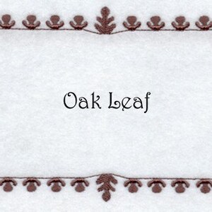 May include: A brown and orange embroidered frame with an oak leaf design. The text "Oak Leaf" is centered in the frame.