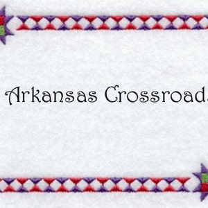 May include: A white background with a red, white, and purple diamond pattern border. The text "Arkansas Crossroads" is centered in the middle of the frame.