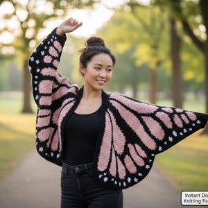 May include: A knitted butterfly wing cardigan in black, pink, and white. The open-front sweater features a butterfly wing design with a black border and pink and white details. The image also includes the text "Instant Download - Knitting Pattern PDF".