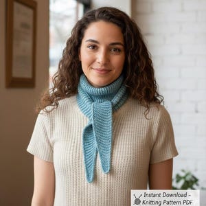 May include: A light blue knitted scarf with a pointed end, worn around the neck. The scarf is made of a soft, textured yarn. The person is wearing a cream-colored ribbed knit shirt. The image includes the text: "Instant Download - Knitting Pattern PDF."
