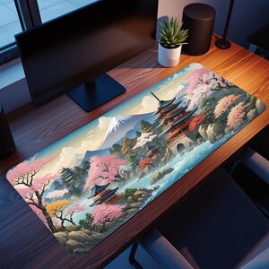 Peut inclure: Tapis de bureau rectangulaire représentant un paysage japonais avec une pagode, des fleurs de cerisier et une montagne. Le tapis présente une rivière bleue, des arbres verts et un ciel bleu clair. La pagode est rouge et marron.
