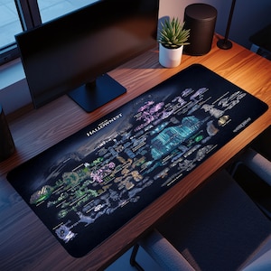 May include: A black desk mat displaying a detailed map of Hallownest, with areas in blue, green, purple, and gold. The text "MAP OF HALLOWNES" is visible. The mat is on a wooden desk, with a computer monitor and other items in the background.