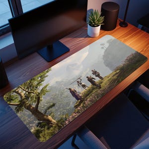 Könnte beinhalten: Rechteckige Schreibtischunterlage mit einer Landschaftsszene, die Figuren auf einem Hügel, Berge und Bäume zeigt. Das Design der Matte hat einen hellblauen Himmel. Die Matte liegt auf einem Holzschreibtisch.
