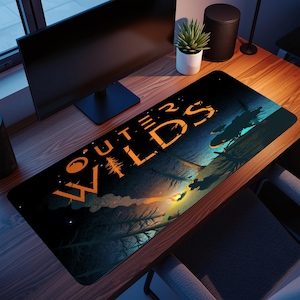 Pode incluir: Tapete de mesa retangular preto com o texto laranja "OUTER WILDS". O design inclui uma cena de floresta com uma fogueira e silhuetas de figuras e árvores. O tapete está em uma mesa de madeira.