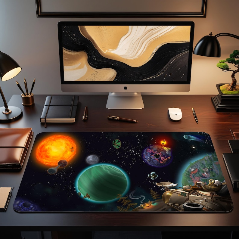 May include: A rectangular desk mat with a colourful space theme. The mat displays planets, stars, and a bright sun against a dark blue backdrop. The mat is on a wooden desk with a computer and accessories.