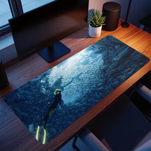 Puede incluir: Alfombrilla de escritorio rectangular con un buzo nadando entre un banco de peces en un océano azul profundo. El buzo lleva un traje de neopreno negro y amarillo. La alfombrilla está diseñada para proteger la superficie del escritorio.
