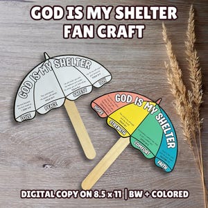 May include: Two umbrella-shaped paper fan crafts with wooden handles. One is black and white, the other is colored in yellow, green, and orange. Both feature the text "GOD IS MY SHELTER" and various Bible verses and words like "LOVE," "PEACE," "SAFETY," "JOY," "HOPE," "STRENGTH," "COMFORT," and "FAITH."