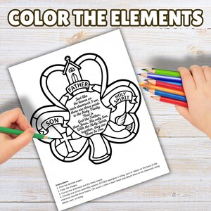 May include: A coloring page with the text "COLOR THE ELEMENTS" at the top. The page features a shamrock design with the words "FATHER", "SON", and "HOLY SPIRIT". A hand is coloring the image with a green colored pencil.
