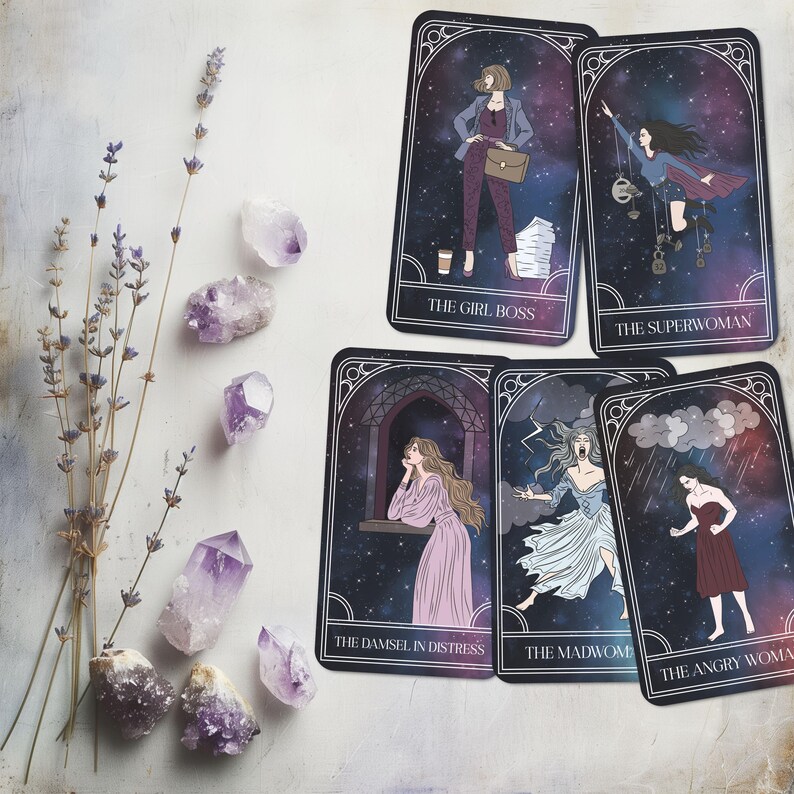 May include: A collection of tarot cards featuring illustrations of women with titles like "The Girl Boss" and "The Superwoman." The cards have a starry background and are framed with a decorative border. Amethyst crystals and lavender sprigs are arranged around the cards.