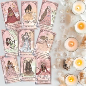 Può includere: Un set di carte dei tarocchi con illustrazioni di figure femminili in varie pose e abiti. Ogni carta ha un titolo, come "La Sacerdotessa" e "La Cacciatrice". Le carte sono disposte con candele accese e cristalli.