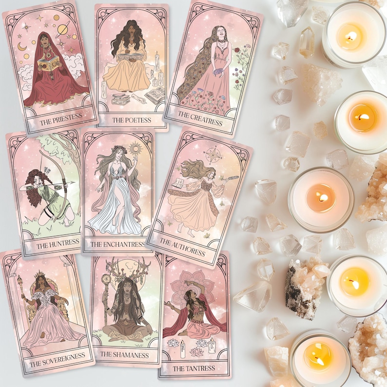 May include: A collection of tarot cards featuring illustrations of female figures in various poses and attire. Each card has a title, such as "The Priestess" and "The Huntress." The cards are arranged with lit candles and crystals.