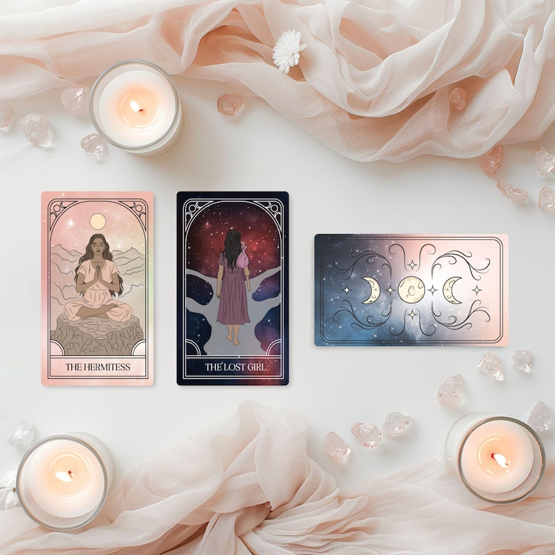 May include: Three tarot cards with illustrations and text, including "THE HERMITESS" and "THE LOST GIRL", are arranged with lit candles, crystals, and draped fabric. The cards feature celestial and feminine imagery in soft colors.