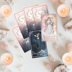 Può includere: Un set di carte dei tarocchi con illustrazioni celesti e mistiche. Le carte raffigurano una sirena, una donna che tiene il sole e le fasi lunari. Candele accese e cristalli circondano le carte, creando un'estetica spirituale.