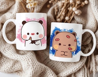 May include: Two white ceramic mugs with cartoon bear illustrations. One mug features a white bear with a pink lipstick, set against a pink background. The other mug has a brown bear with kiss marks, set against a blue background.