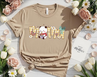 May include: Tan t-shirt with the word "mama" in a yellow plaid design, decorated with a panda bear, flowers, and butterflies. A card with "Happy Mother's Day" is next to the shirt.