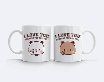 May include: Two white ceramic mugs with the text "I LOVE YOU BECAUSE YOU ARE YOU." One mug features a panda bear illustration, the other a brown bear. Both have a cute, cartoonish design.