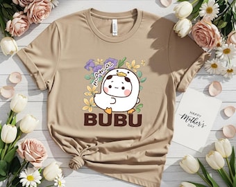 May include: A tan t-shirt featuring a cartoon duck character with the word "BUBU" below it. The design includes the word "mama" and floral elements. A card with "Happy Mother's Day" is visible.