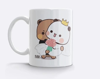 May include: White ceramic mug featuring a cartoon panda and bear couple. The panda wears a crown and wedding dress, holding a bouquet. The bear is in a tuxedo. The mug has the text "BUBU & DUDU".
