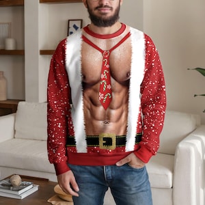 Peut inclure: Un sweat-shirt rouge à manches longues avec une impression photoréaliste d'un torse musclé, une cravate rouge ornée de sucres d'orge, une bordure en fausse fourrure blanche sur les côtés et une ceinture noire à boucle dorée à la taille.