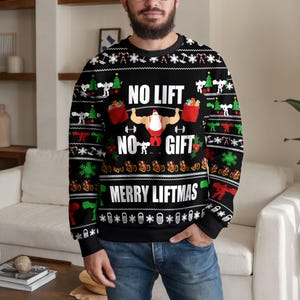 Puede incluir: Una sudadera negra de manga larga con cuello redondo que presenta un gráfico de un Santa Claus musculoso levantando una barra de pesas. El texto dice NO LIFT NO GIFT MERRY LIFTMAS. El diseño incluye copos de nieve, mancuernas, árboles y bolsas de regalo.
