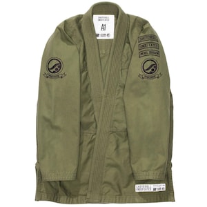 May include: Olive green martial arts gi with black embroidered patches. The gi features the text "SHOYOROLL UNDEFEATED REBEL DIVISION" and an "A1" size label. The gi is designed for martial arts training and competition.