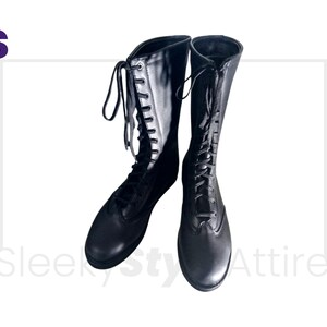 Puede incluir: Un par de botas negras hasta la rodilla con dise&ntilde;o de cordones. Las botas tienen una puntera redondeada y un acabado liso y pulido. Las botas se muestran sobre un fondo blanco.