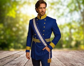 May include: A royal blue military-style jacket with gold trim and buttons. The jacket features a white and blue sash and a gold-trimmed belt. The sleeves have gold cuffs. The jacket is worn with dark pants. The background is a blurred outdoor scene.