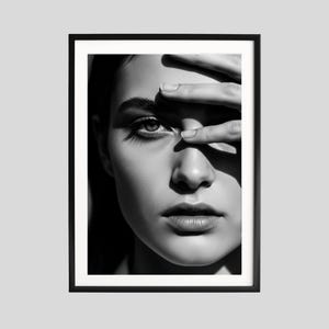 May include: Black and white framed portrait of a person shielding their eyes with their hand. The image is a close-up of the person's face, with a focus on the eye and lips. The artwork is a modern, minimalist style.