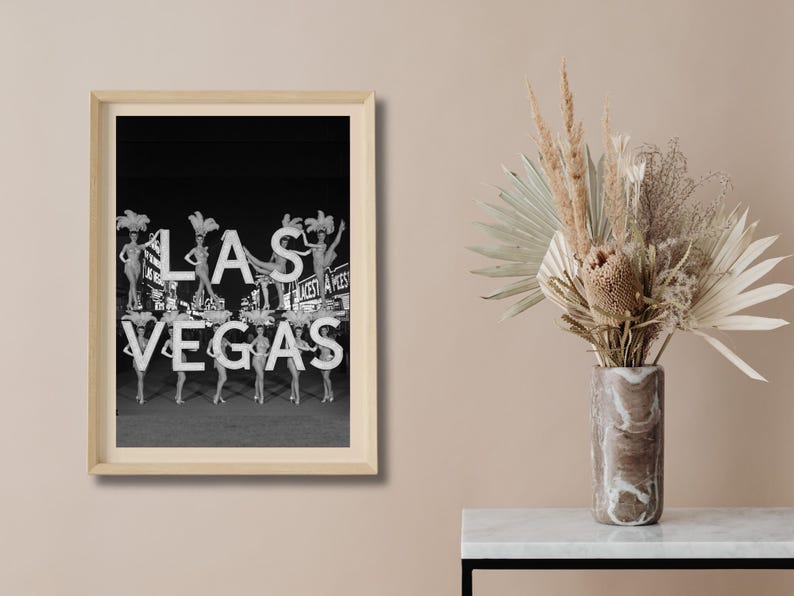 May include: Black and white framed print featuring the word "LAS VEGAS" in large, illuminated letters. The image includes showgirls and a vintage aesthetic, evoking a sense of classic entertainment and the iconic city.