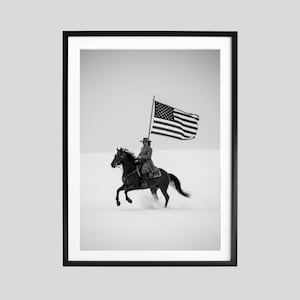 Puede incluir: Impresión enmarcada en blanco y negro de un vaquero a caballo sosteniendo una gran bandera estadounidense. El caballo galopa por un paisaje nevado. El vaquero lleva sombrero y abrigo. La bandera ondea al viento.