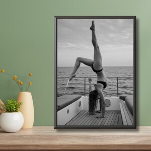 Peut inclure: Tirage encadr&eacute; en noir et blanc d'une personne faisant le poirier sur le pont d'un bateau. La personne porte un bikini noir. L'arri&egrave;re-plan montre la mer et le ciel.