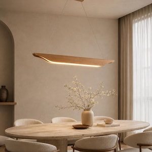 May include: A linear pendant light fixture crafted from light-toned wood, suspended by thin wires from a rectangular ceiling mount. The fixture features a long, curved wooden body with an integrated LED light strip emitting a warm glow downward.
