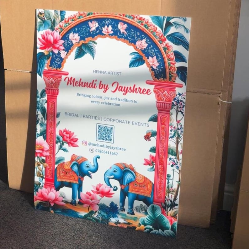 May include: A decorative sign featuring the text "Mehndi by Jayshree" with floral and elephant illustrations. The sign has a white background with red pillars, a blue arch, and pink flowers. The sign also includes contact information.