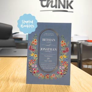 May include: A blue wedding booklet with a floral design and gold detailing. The booklet includes the names Bethan and Jonathan, and the date 29 May 2025. The text "Stapled Booklets" is in a blue bubble. The booklet is for a wedding ceremony.