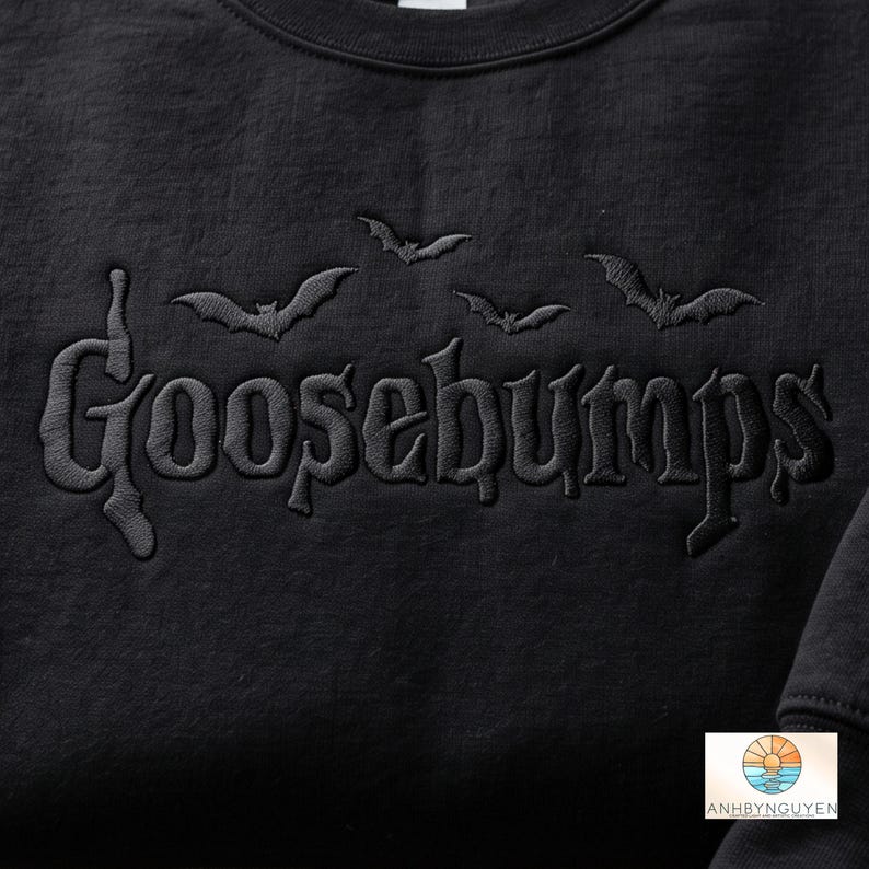 May include: A black sweatshirt featuring the word Goosebumps embroidered in a matching black thread across the chest. Above the text, three small black bats are embroidered in a row. The fabric has a visible texture and a matte finish.