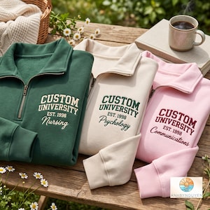 Puede incluir: Tres sudaderas con cremallera de cuarto en verde oscuro, crema y rosa claro. Cada una presenta el texto bordado CUSTOM UNIVERSITY EST. 1998 con una especialidad: Nursing, Psychology o Communications. Las prendas tienen puños y cuellos acanalados.
