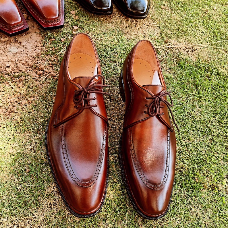 Brown derby shoes for men with smooth leather finish and open lacing design suitable for US, UK, Canada, Australia, Switzerland, and Pakistan markets.