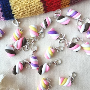 Puede incluir: Una colección de abalorios con forma de malvavisco de colores con cierres de langosta plateados. Los abalorios son de varios colores, incluyendo rosa, blanco, amarillo, morado y marrón. Los abalorios son perfectos para añadir un toque divertido y caprichoso a cualquier proyecto.