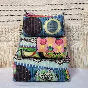 May include: Three patterned fabric pouches stacked. The top pouch features a black polka dot design with blue and yellow circles. The middle pouch has a strawberry pattern. The bottom pouch has a floral design. The pouches are in a variety of bright colours.
