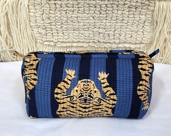 May include: A rectangular quilted zippered pouch featuring a repeating pattern of tan tigers with black stripes against a background of alternating vertical navy blue and light blue stripes. The fabric has a visible grid-like stitched texture.