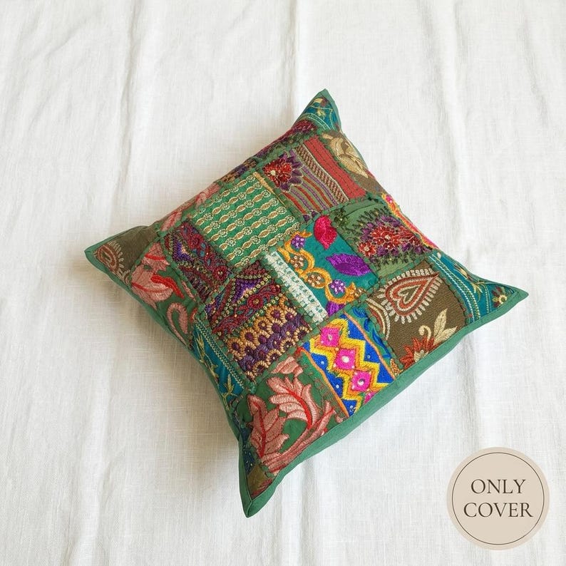 May include: A square throw pillow cover featuring a patchwork design of various green, red, yellow, and purple fabric segments. The surface is decorated with intricate embroidery, sequins, and beadwork in floral and geometric patterns. Text reads ONLY COVER.