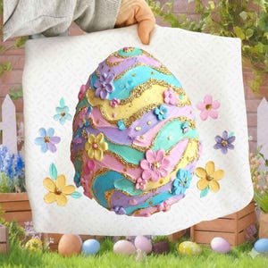 May include: A large, decorative Easter egg with a pastel color scheme of pink, yellow, blue, and purple. The egg is adorned with gold glitter and floral embellishments. The egg is held up by a person.