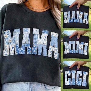 May include: Black sweatshirt with the word "MAMA" in blue patchwork letters. The letters are made of various blue floral and gingham fabrics. Additional sweatshirts with "NANA", "MIMI", and "GIGI" in similar styles are also shown.