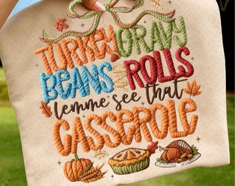 May include: A beige Thanksgiving-themed decorative pillow with embroidered text and illustrations. The text reads "TURKEY GRAVY BEANS ROLLS lemme see that CASSEROLE" in orange, blue, and red. Illustrations include a pumpkin, pie, and turkey.
