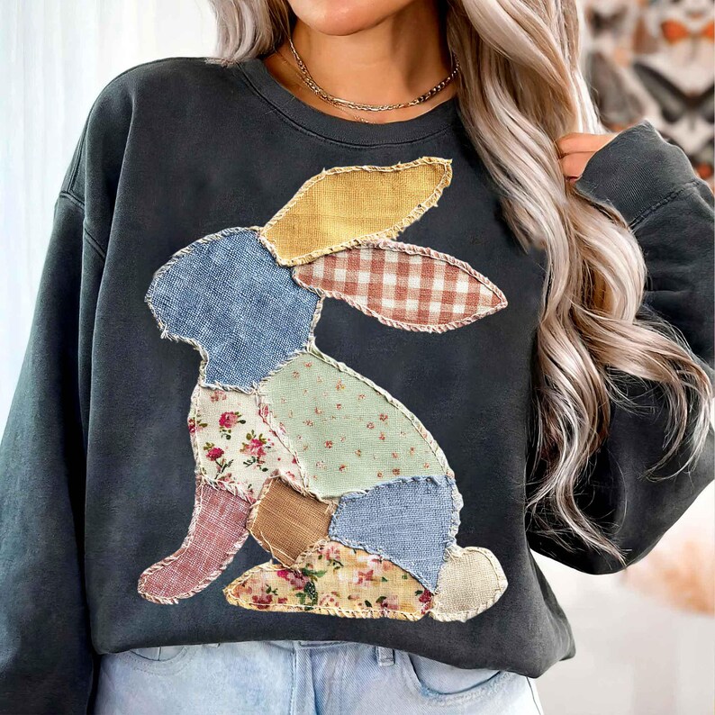 May include: Dark gray sweatshirt featuring a patchwork bunny design. The bunny is composed of various fabric patterns, including floral, gingham, and solid colors. The sweatshirt has a crew neck and long sleeves, perfect for casual wear.
